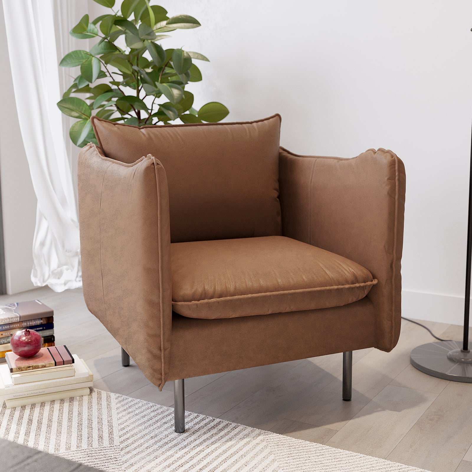 Cassian PU Leather Armchair in Chocolate Brown, featuring warm upholstery, broad padded armrests, slim metal legs, surrounded by a houseplant, books, and an apple, on a light-wood floor.