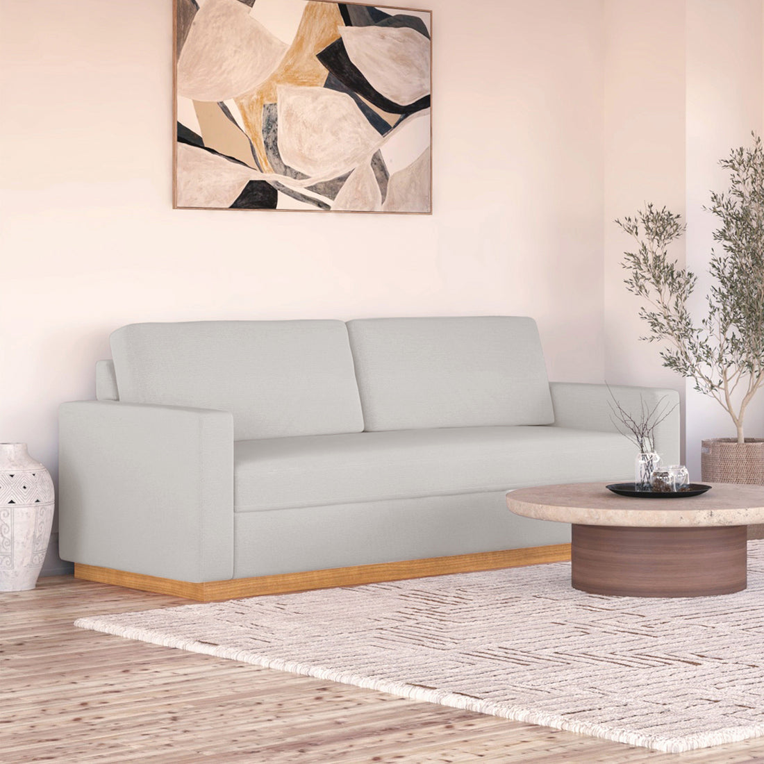 Celeste 3 Seater Hardwood Fabric Sofa with removable cushions and wood accent legs, showcasing its sturdy frame and sleek design in an interior setting with a painting and a studio couch nearby.