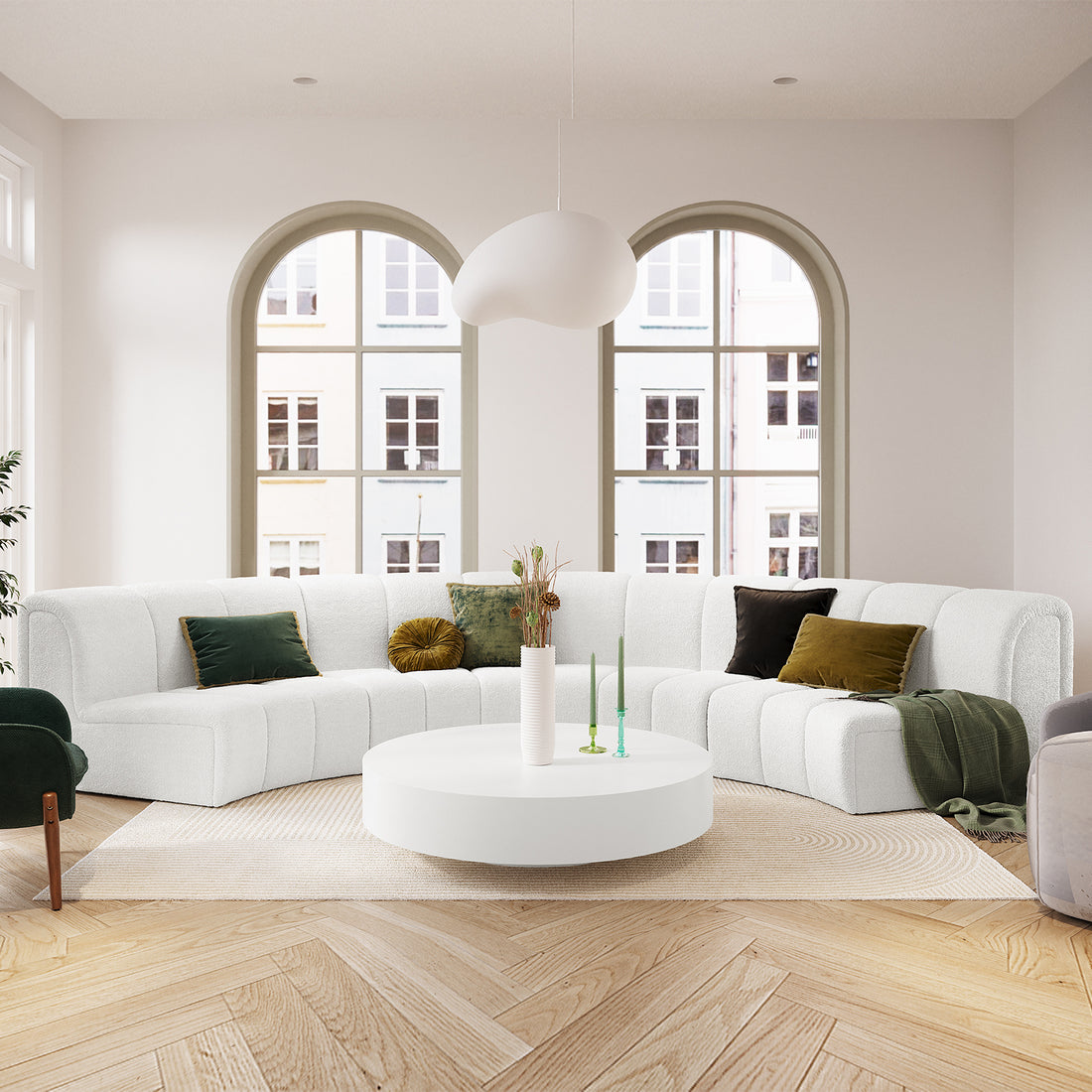 Corina 4 Seater Modular Boucle Sofa in Cream White, featuring a curved design with deep green and mustard accent pillows, set in a bright, minimalist living room with arched windows and parquet flooring.
