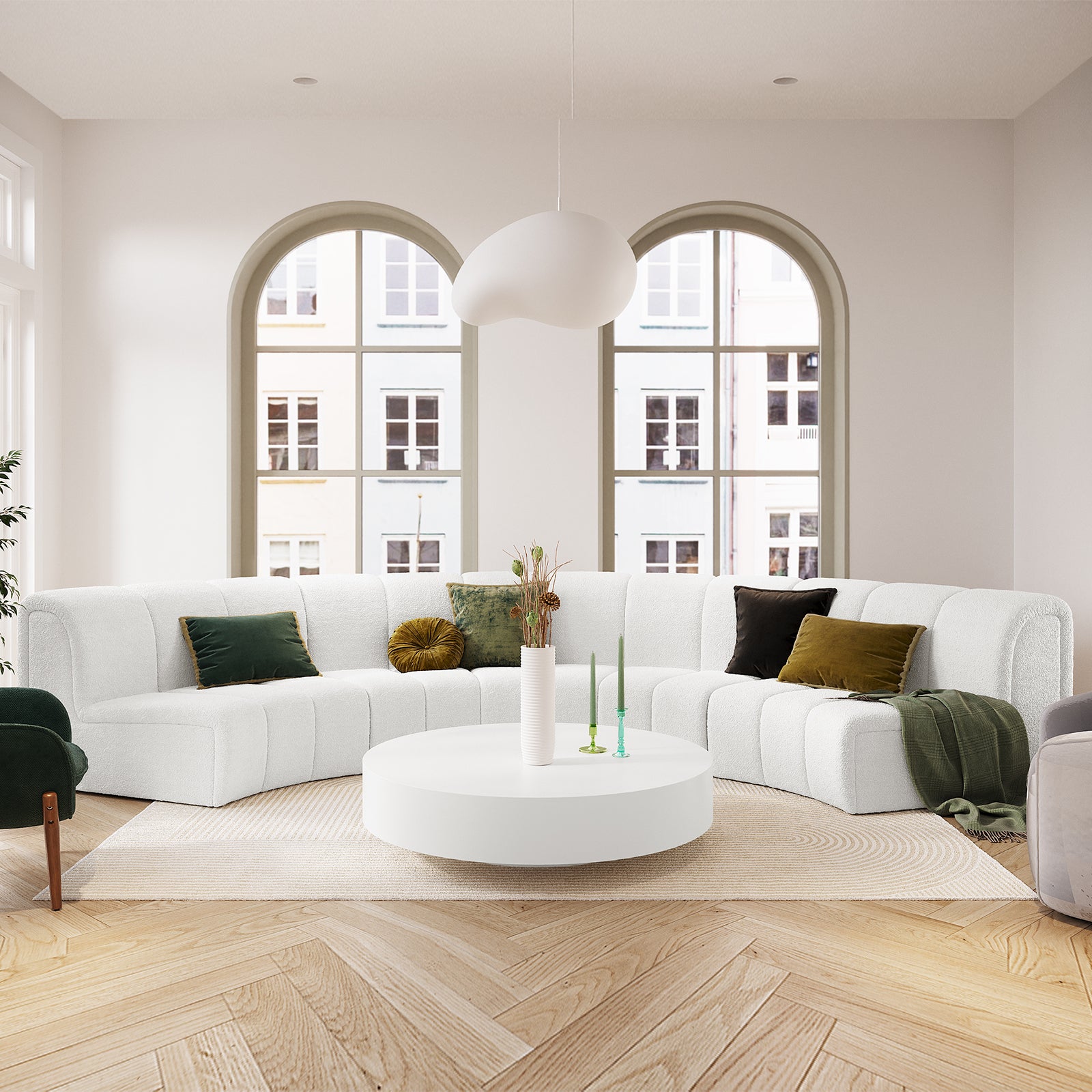 Corina 4 Seater Modular Boucle Sofa in Cream White, featuring a curved design with deep green and mustard accent pillows, set in a bright, minimalist living room with arched windows and parquet flooring.