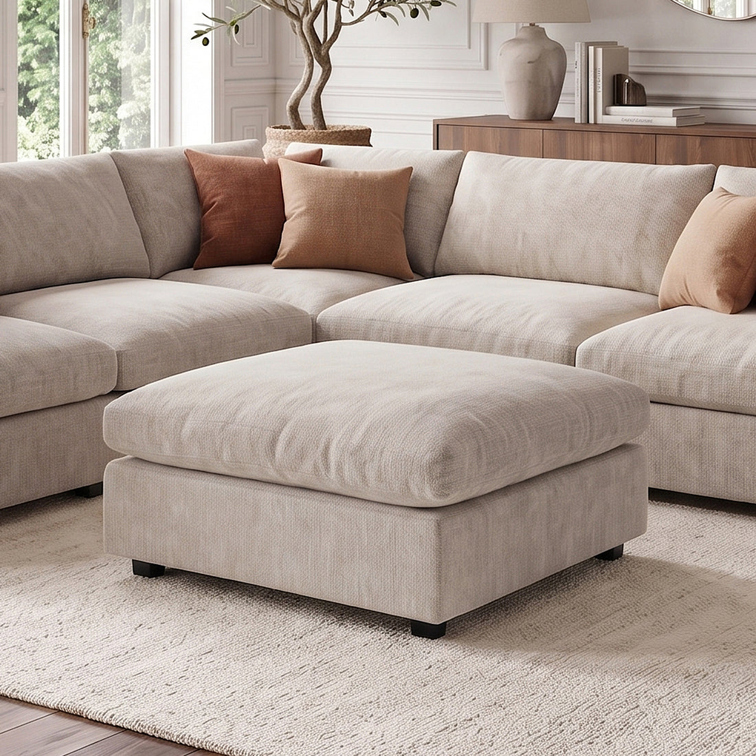 Beige sectional sofa with matching ottoman in a styled living room.