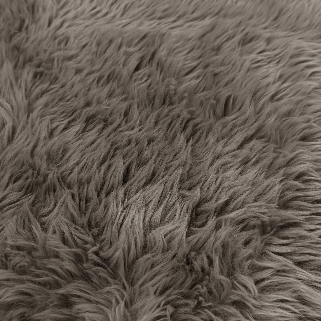 A macro close-up texture view of the taupe faux-fur or sheepskin material, showing the dense, long-pile fibers.