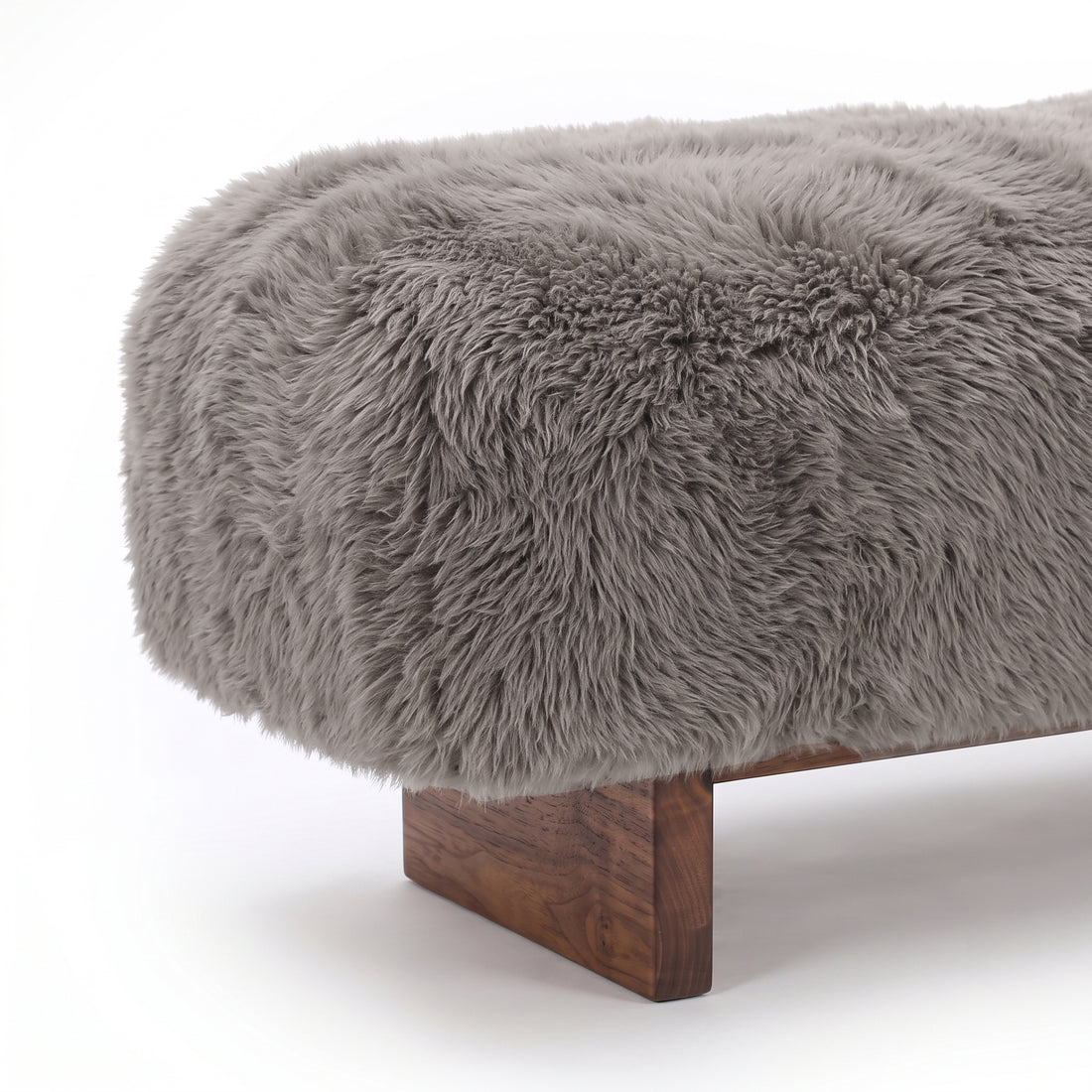 A close-up detail view of the taupe faux-fur or sheepskin upholstered bench, highlighting the plush, long-pile texture of the fabric meeting the clean edge of the dark wooden block leg against a plain white background