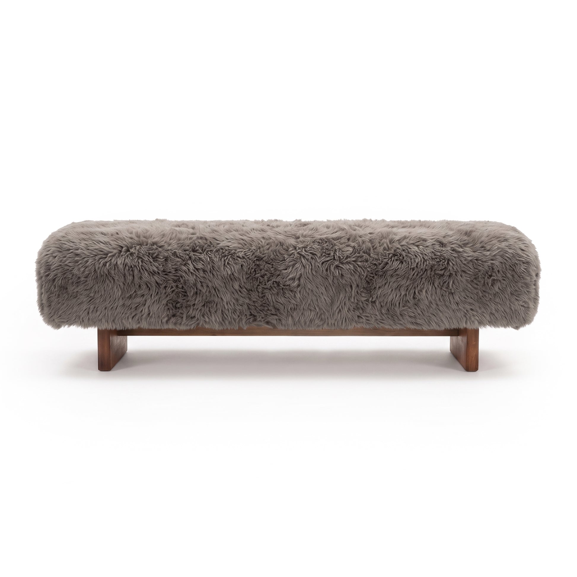 A straight-on view of the taupe faux-fur or sheepskin upholstered bench, showcasing its long-pile plush texture and low dark wooden block legs against a clean white background.