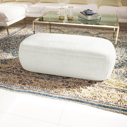 Jamie 110cm Bouclé Fabric Ottoman in Cream White, a softly rounded upholstered piece on a patterned rug, perfect for relaxation, with a solid wood frame and elegant design.