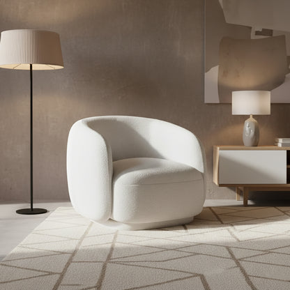Janelle Bouclé Curved Accent Chair in White, featuring a rounded design, premium bouclé upholstery, and placed on a geometric-patterned rug, alongside a black floor lamp and a light wood side console.