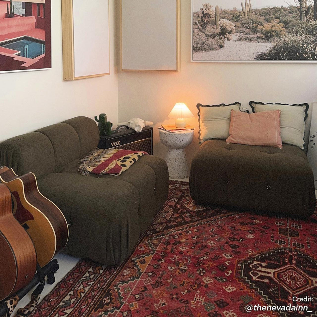 Keila Modular Tufted Boucle Single Sofa in Green sits on a patterned rug beside guitars, near a side table with books and lamp, framed prints above complete the cozy setup.