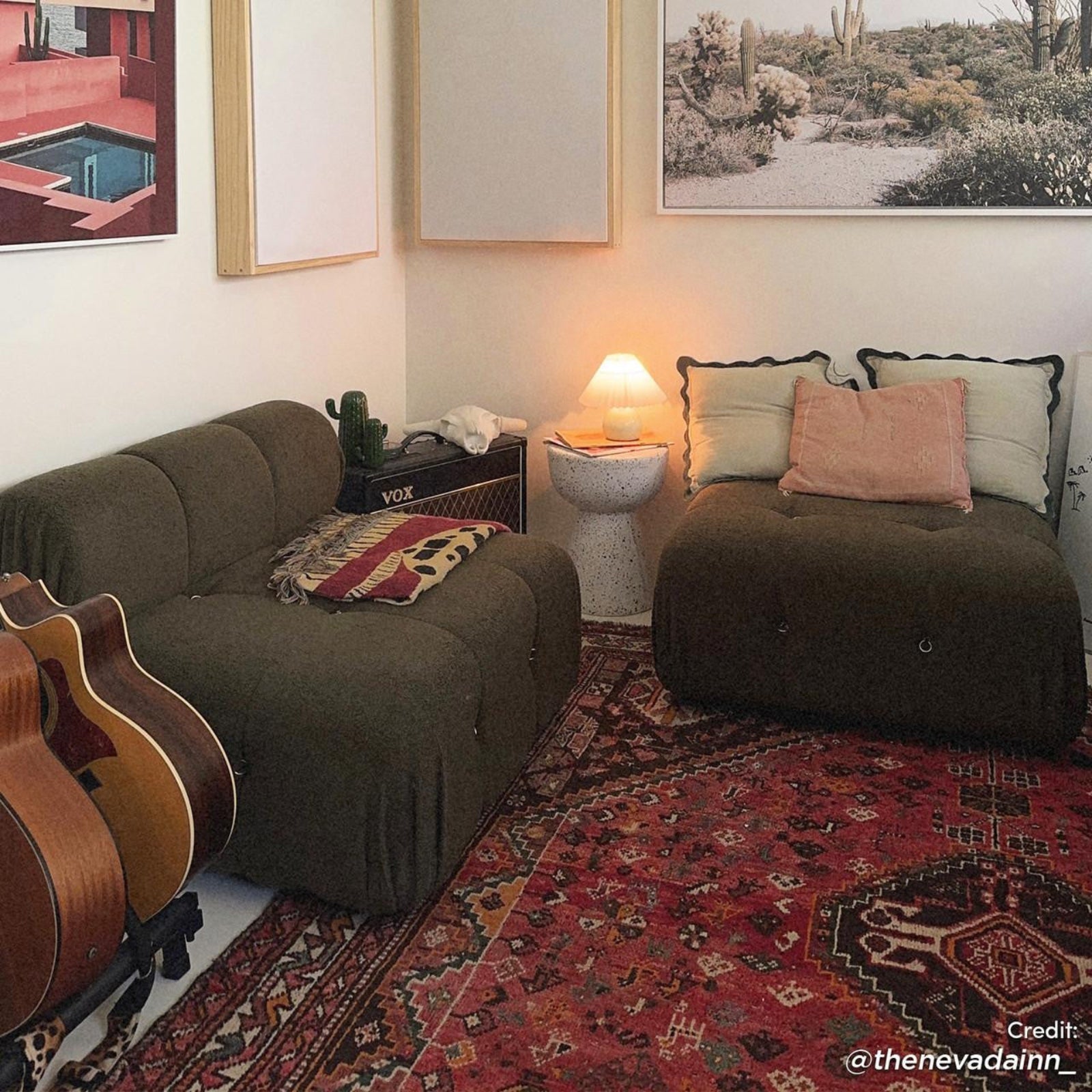 Keila Modular Tufted Boucle Single Sofa in Green sits on a patterned rug beside guitars, near a side table with books and lamp, framed prints above complete the cozy setup.