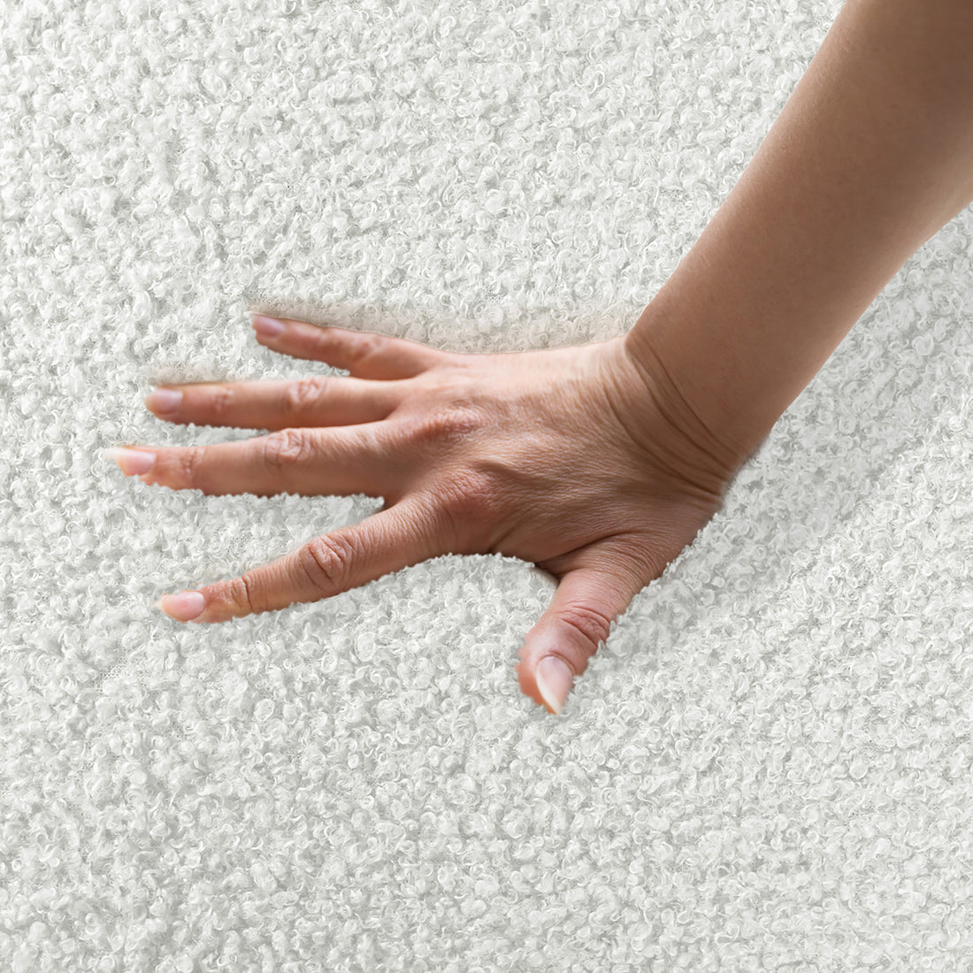 A hand presses the plush, curly-textured surface of the Lyana 7 Seater Boucle Sofa Set in Cream White, highlighting its luxurious, cushioned comfort and sophisticated design.