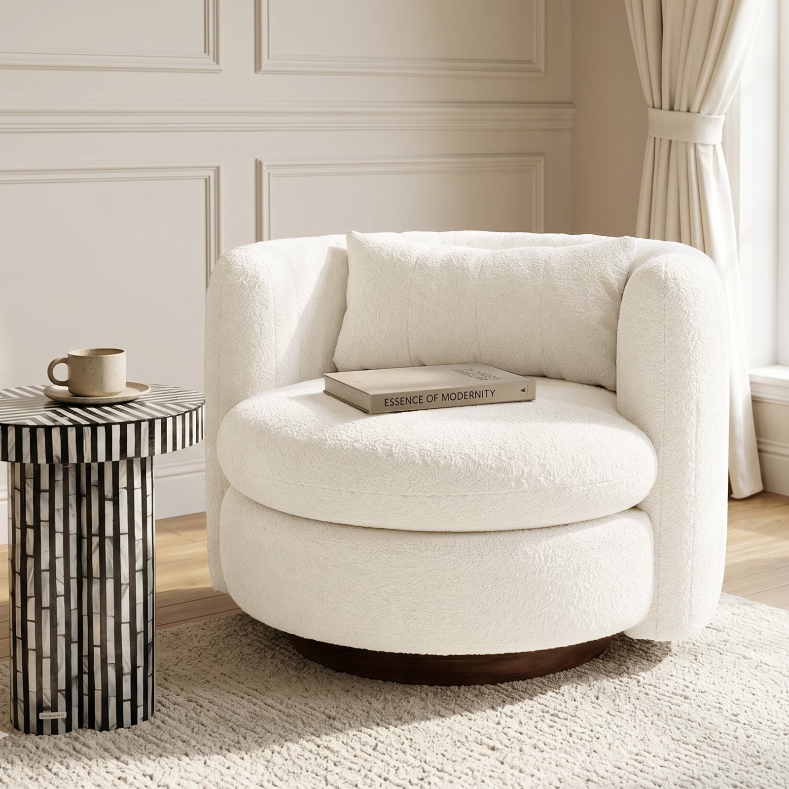 Marvik 360° Swivel Accent Chair in Cream White features a softly-curved design with boucle upholstery, set in a neutral paneled room alongside a black-and-white striped side table.
