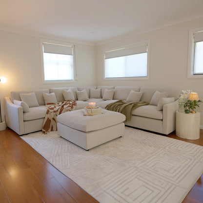 Millie 6-Seater Fabric Corner Chaise Sofa Light Beige displayed in a cozy living room setting, showcasing its spacious, modular design with plush cushions on a sleek, comfortable couch.