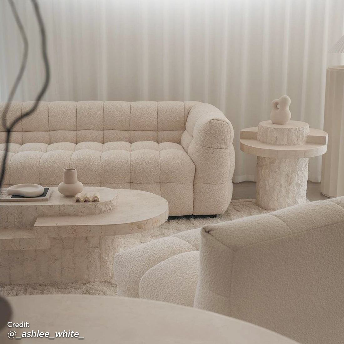 Norah 3 Seater Boucle Sofa in Cream White, featuring plush grid-tufting and boucle upholstery, is showcased with a matching lounge chair, stone-look coffee table, and shag-style rug in a serene living room setting.