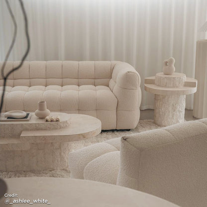 Norah 3 Seater Boucle Sofa in Cream White, featuring plush grid-tufting and boucle upholstery, is showcased with a matching lounge chair, stone-look coffee table, and shag-style rug in a serene living room setting.