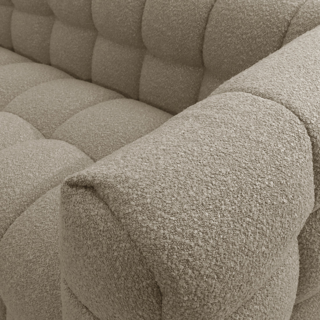 Close-up of the Norah 5-Seater Boucle Sofa Set with Armless Chairs in warm beige, showcasing the textured, tufted upholstery meeting the armrest, highlighting its luxurious boucle fabric and plush comfort.