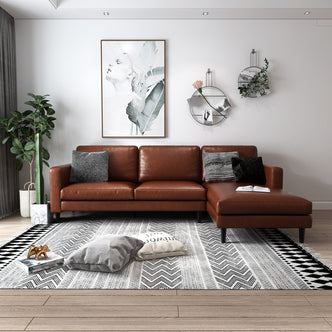 Nornas 3 Seater PU Leather Sofa with Chaise Brown featuring plush cushions and a sleek design, shown with a grey pillow on its brown leather surface, highlighting its luxurious appeal and spacious seating.