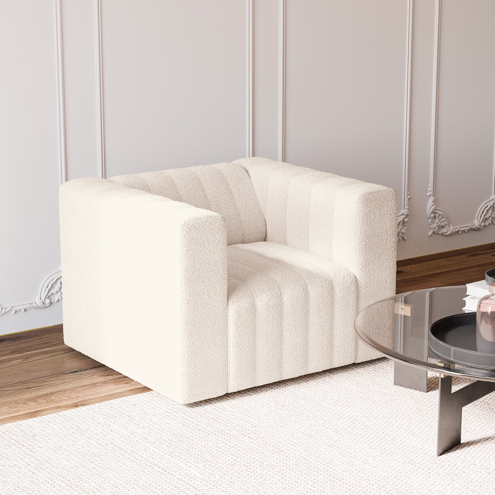 Parisa 1 Seater Tufted Boucle Single Sofa in Cream White, cube-shaped with vertical channeling, rests on a textured rug, near a glass-top table with black legs and decorative items.