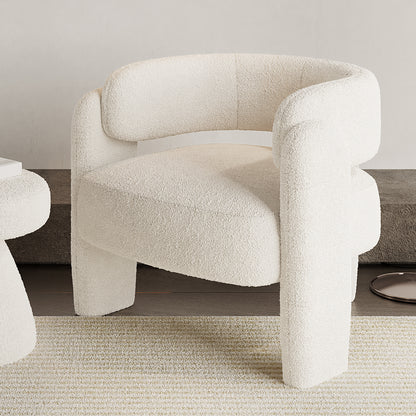 Seto Bouclé Curved Occasional Accent Chair in eggshell white, featuring a rounded backrest and arms, thick cushioning, and three chunky legs on a light-toned rug with a matching side table partially visible.