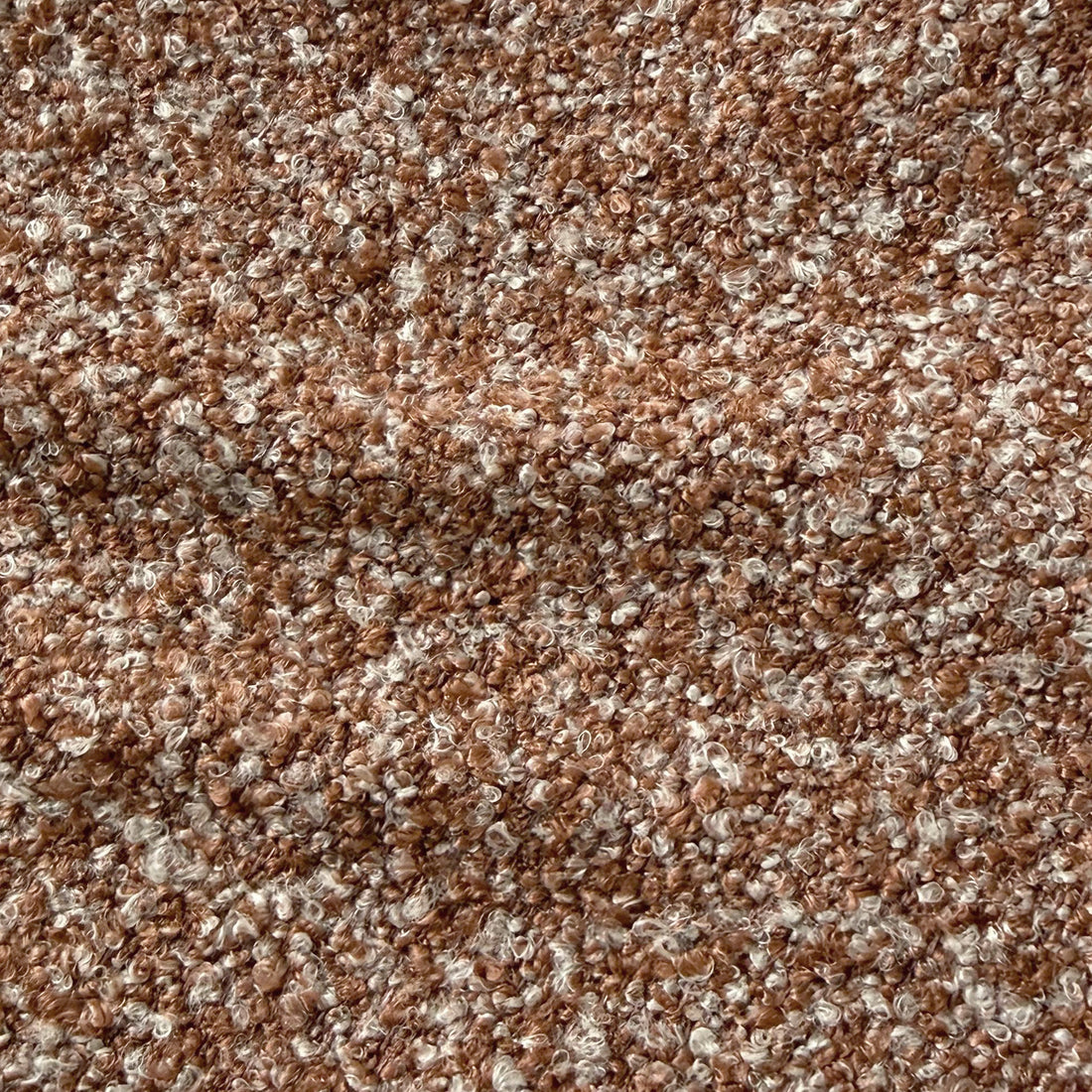 Close-up of the Sornel Boucle Upholstered Accent Chair in Coral, showcasing its textured boucle fabric with looped, curly fibers, highlighting the chair's tactile and high-density comfort design.
