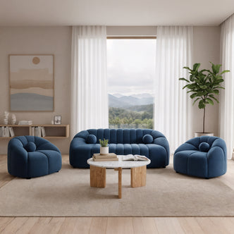 Trina 5 Seater Tufted Velvet Sectional Sofa in Blue, featuring plush velvet upholstery, channel tufting, and a curved silhouette, flanked by matching club chairs, coffee table with books, plant, and open book.