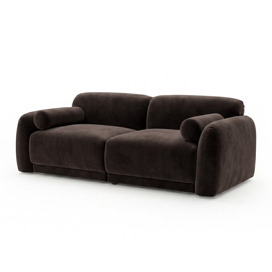 Dark brown velvet sofa with rounded armrests and cylindrical bolster pillows on white background