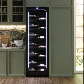 K155G 155 Bottle Built-In Wine Fridge with Lock in Black, featuring LED-lit shelves filled with wine bottles, sits within sage-green cabinetry, adjacent to a marble countertop holding kitchen essentials.