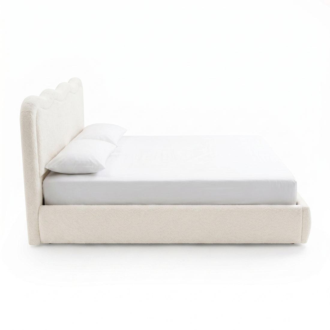 Side view of upholstered bed with pillows on white background