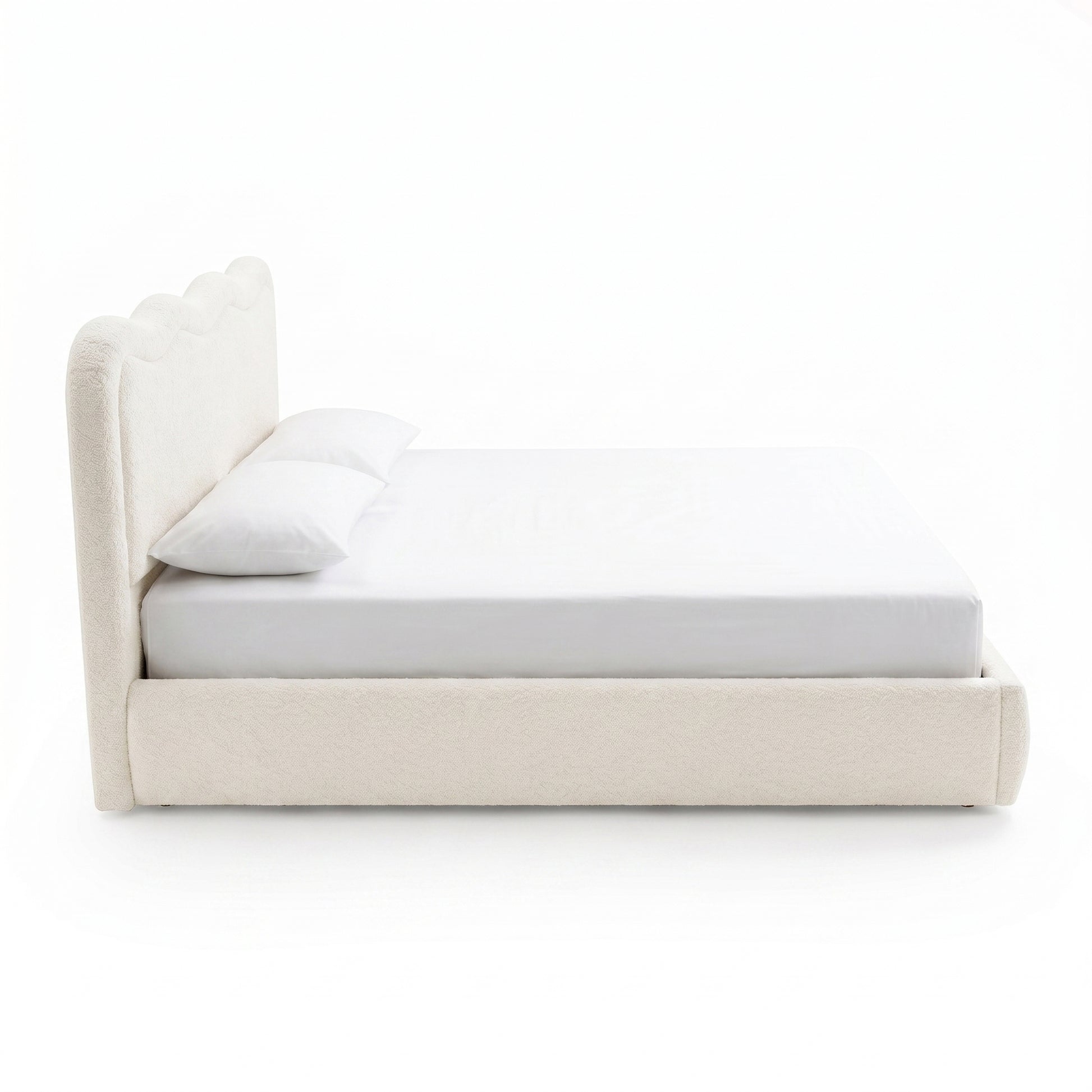 Side view of upholstered bed with pillows on white background