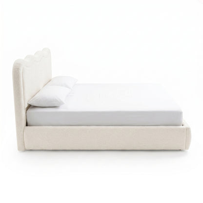 Side view of upholstered bed with pillows on white background