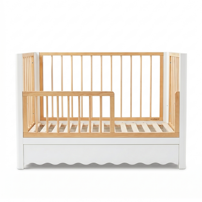 Modern white and natural wood baby crib with scalloped base on white background