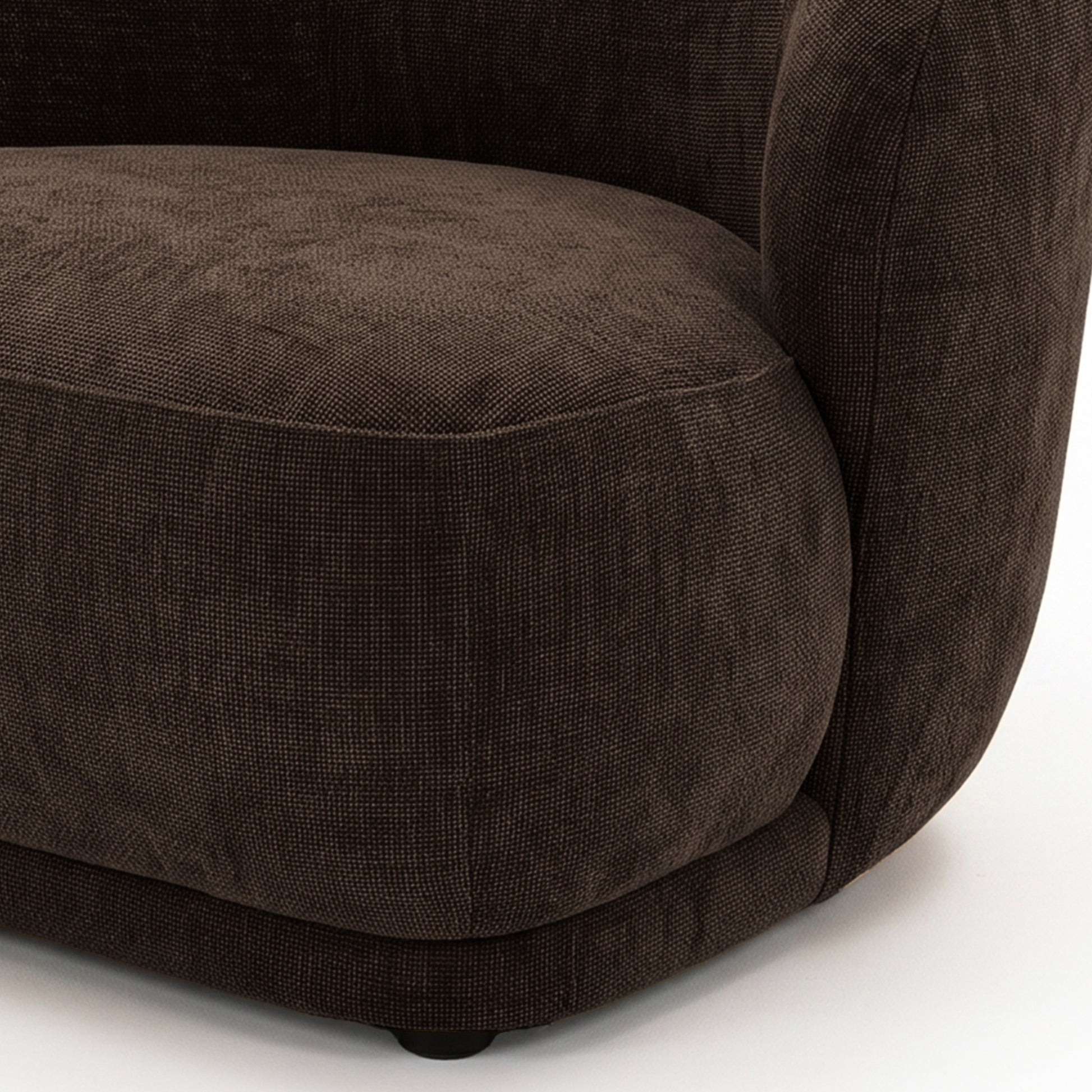 Close-up of the lower half and side of a cocoa brown accent chair on a white background.