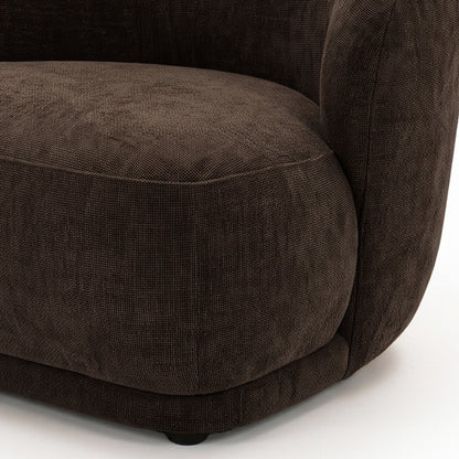 Close-up of the lower half and side of a cocoa brown accent chair on a white background.