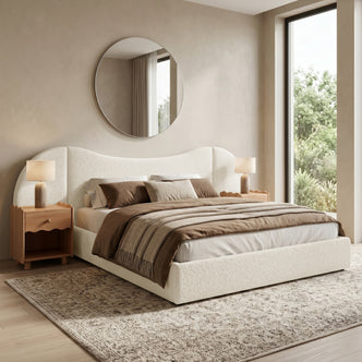 Cream upholstered bed in a modern, sunlit bedroom with nightstands and a mirror