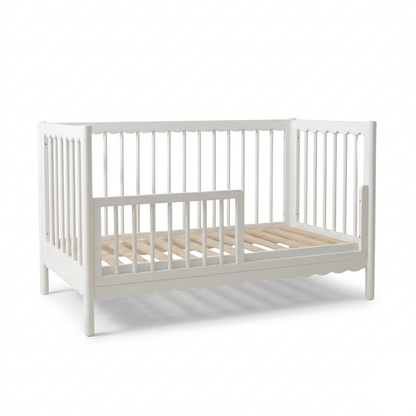 White crib with U-shaped front rail against a white background