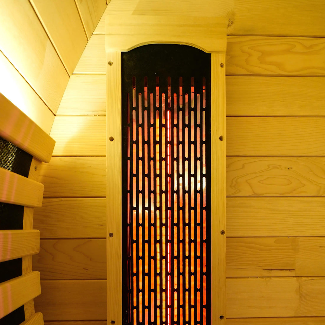 Close-up of a black infrared heater panel in a wooden sauna wall