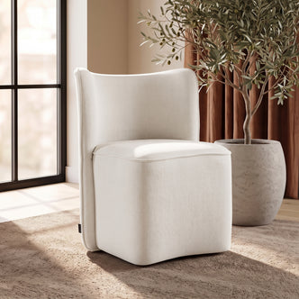 A white upholstered accent chair styled in a bright living room setting