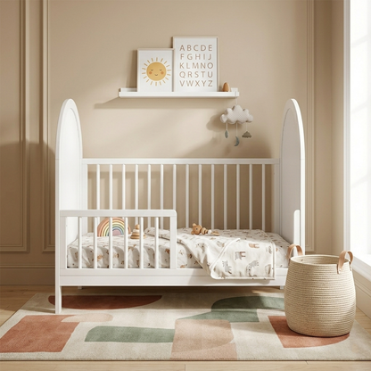 White toddler bed in a cozy, decorated nursery with a toy, rainbow pillow, and wall decor