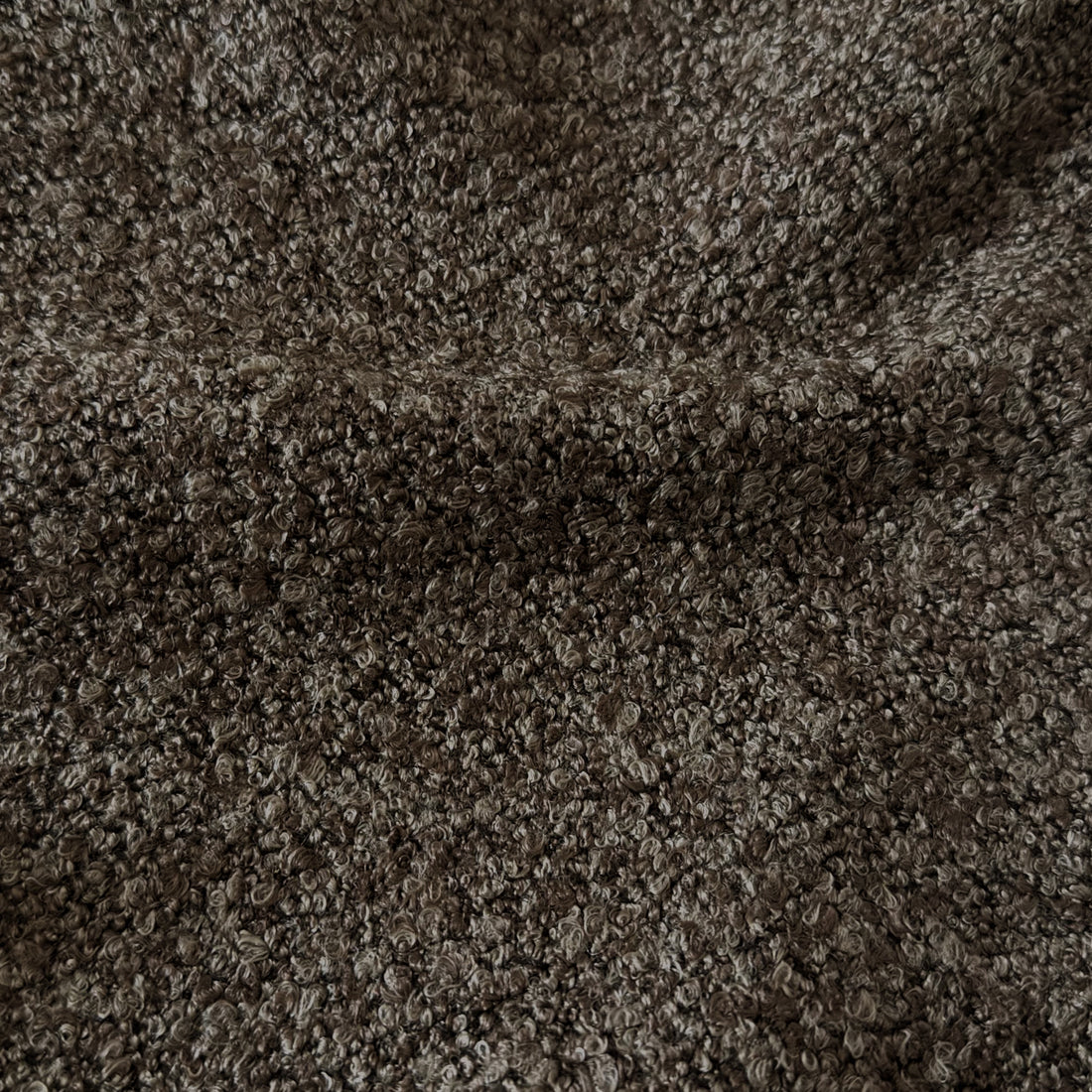 Very close-up view of dark brown bouclé fabric texture