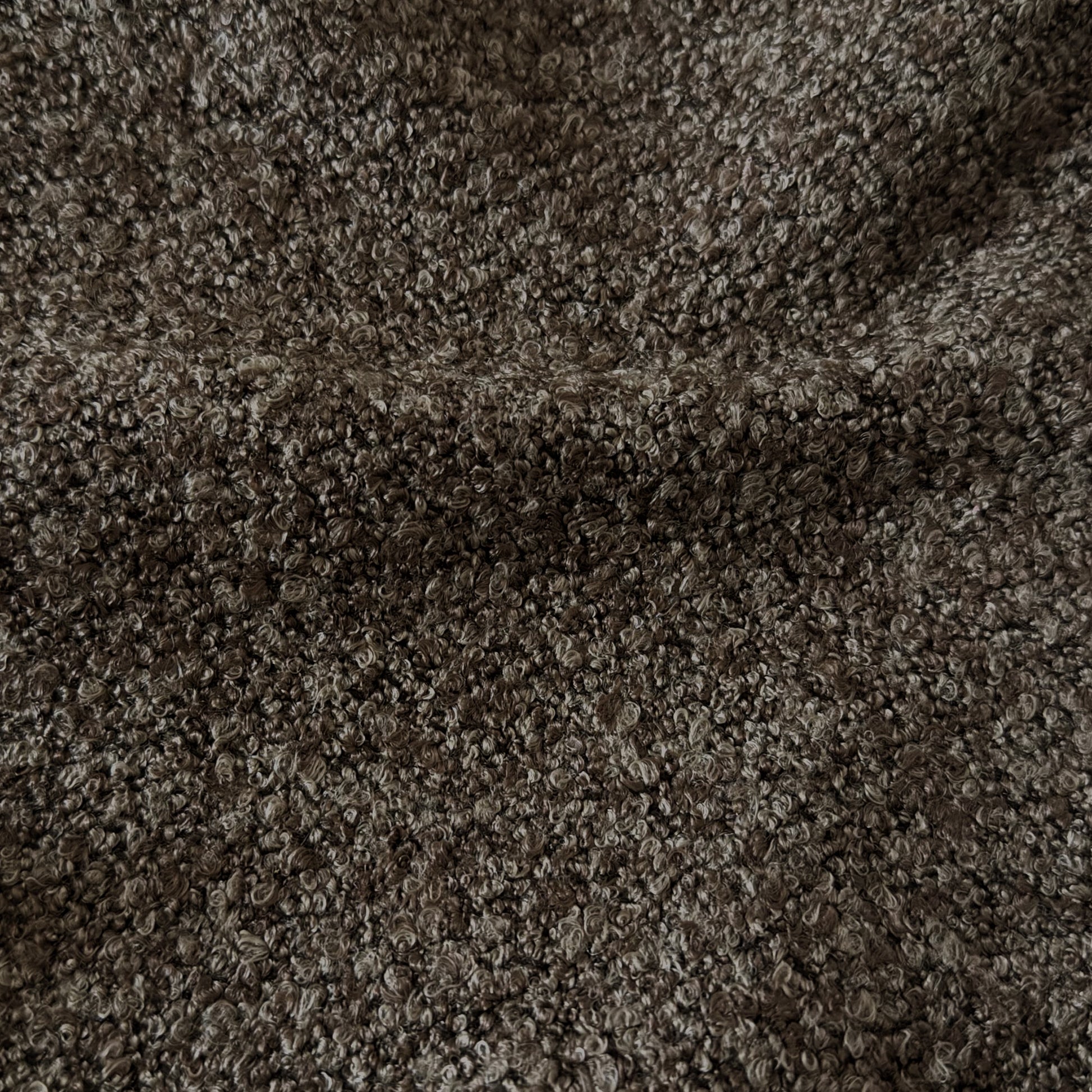Very close-up view of dark brown bouclé fabric texture