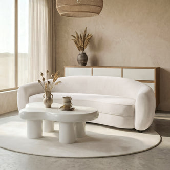Curved white sofa in a modern living room with coffee tables and décor