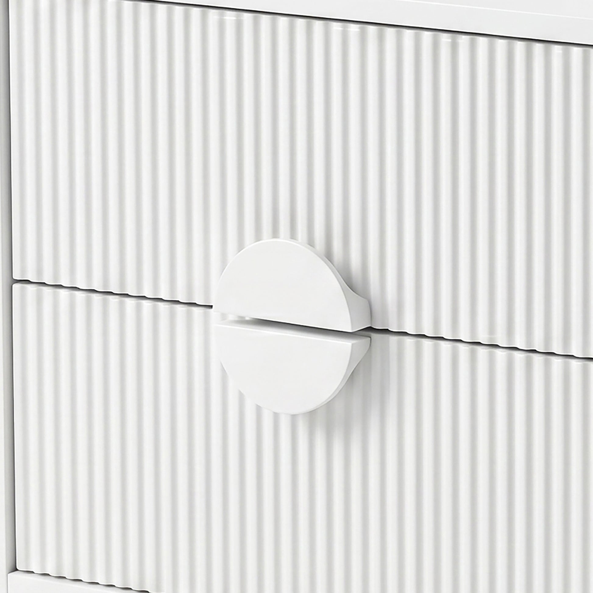 Close-up of white drawer fronts with vertical grooves and circular handle