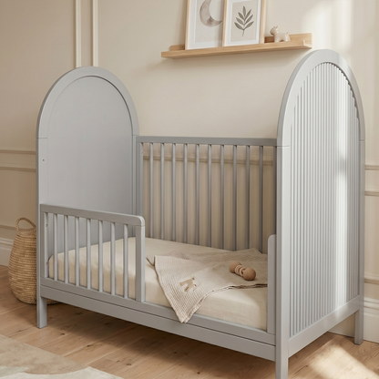 Gray crib in neutral-toned nursery with blanket and plush toy