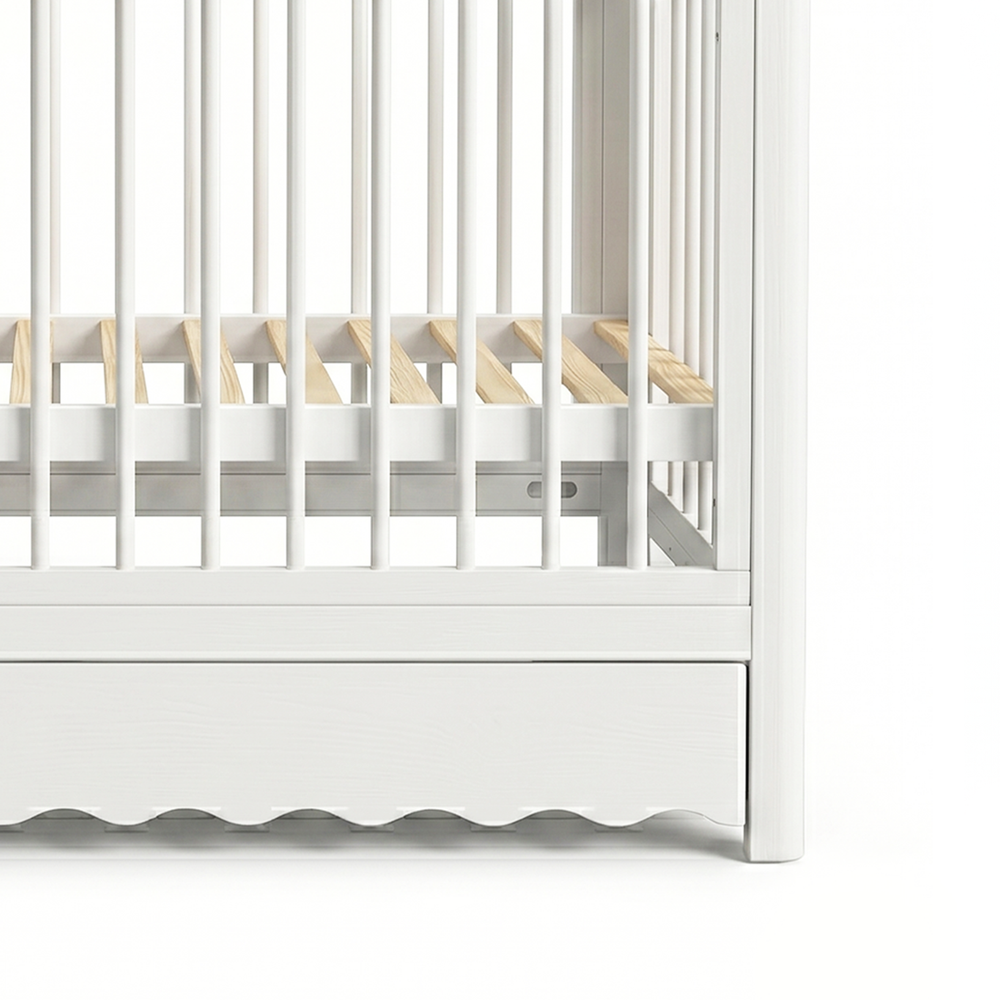 Close-up of crib base, slats, and scalloped drawer edge