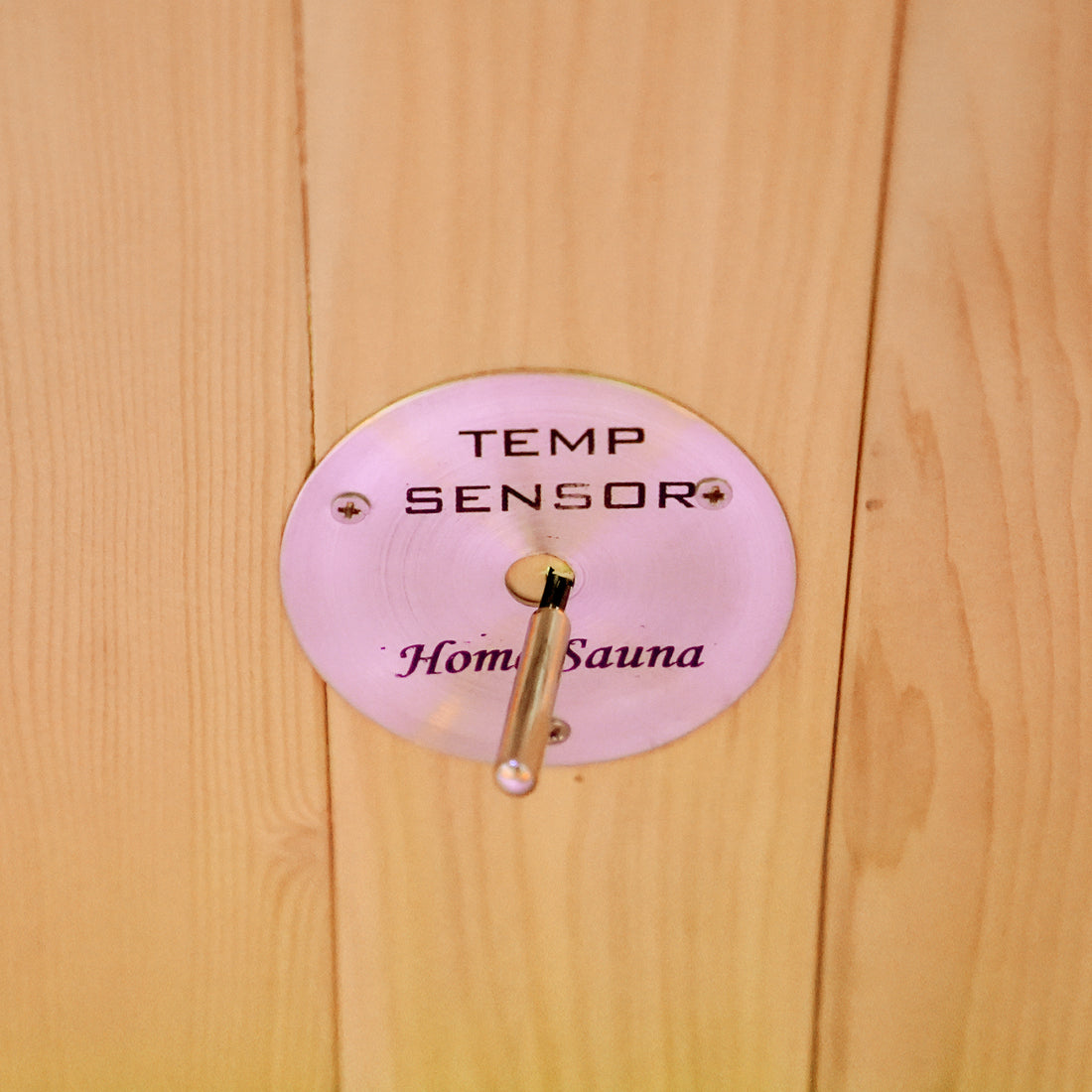 Close-up of a temperature sensor labeled Home Sauna mounted on a wooden wall