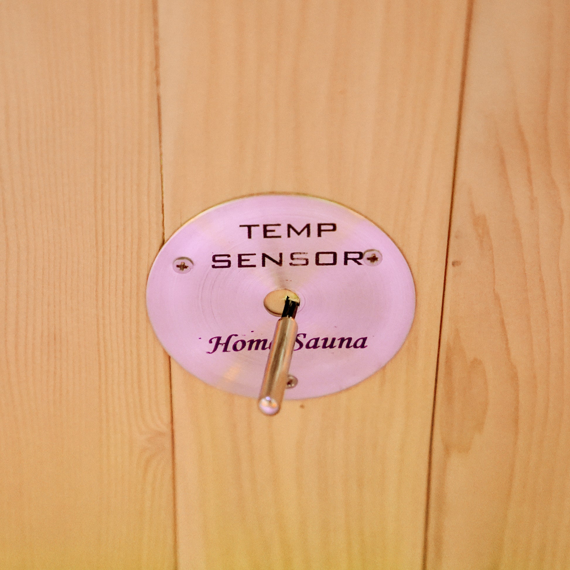 Close-up of a temperature sensor labeled Home Sauna mounted on a wooden wall