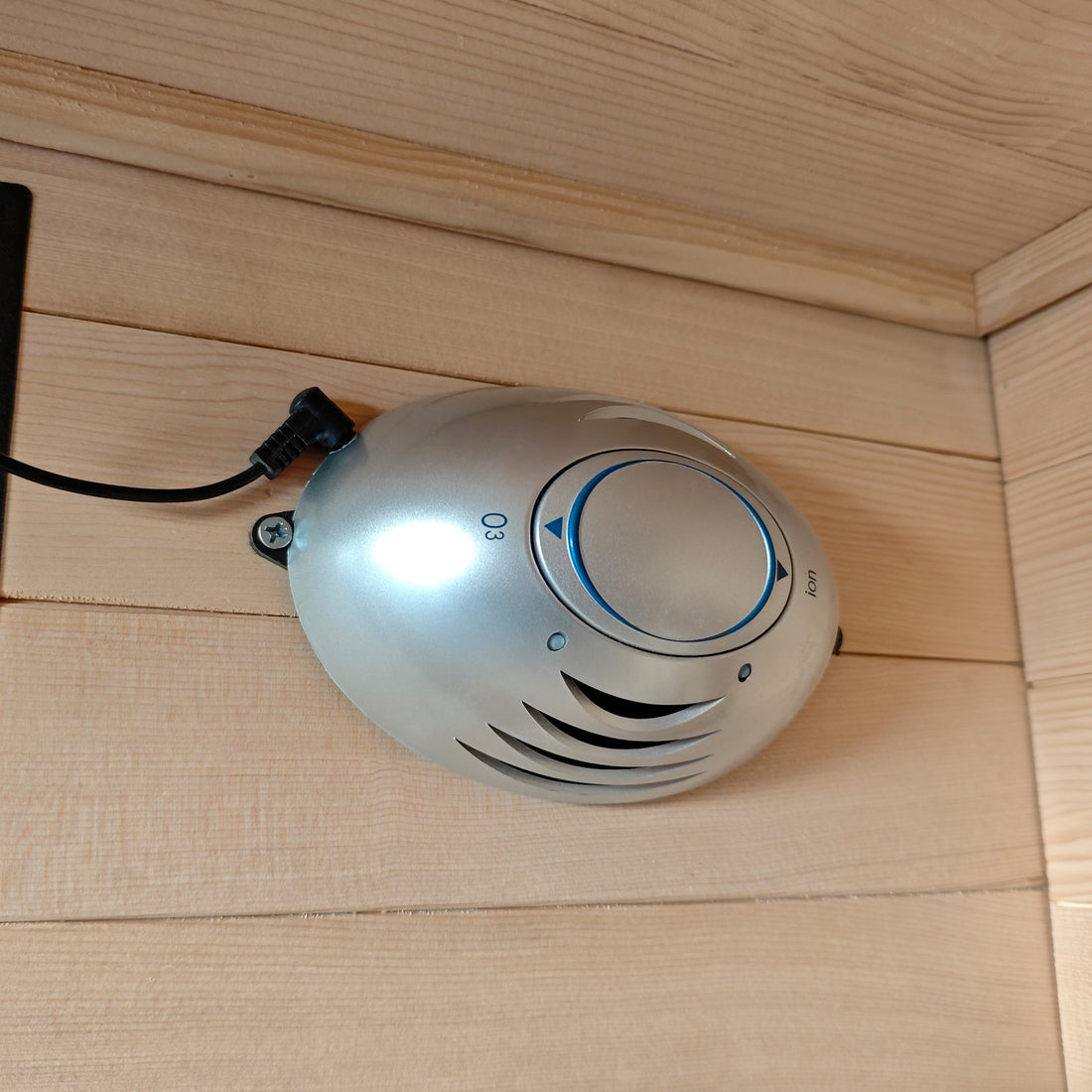 Compact oval electronic control device mounted on a wooden wall.