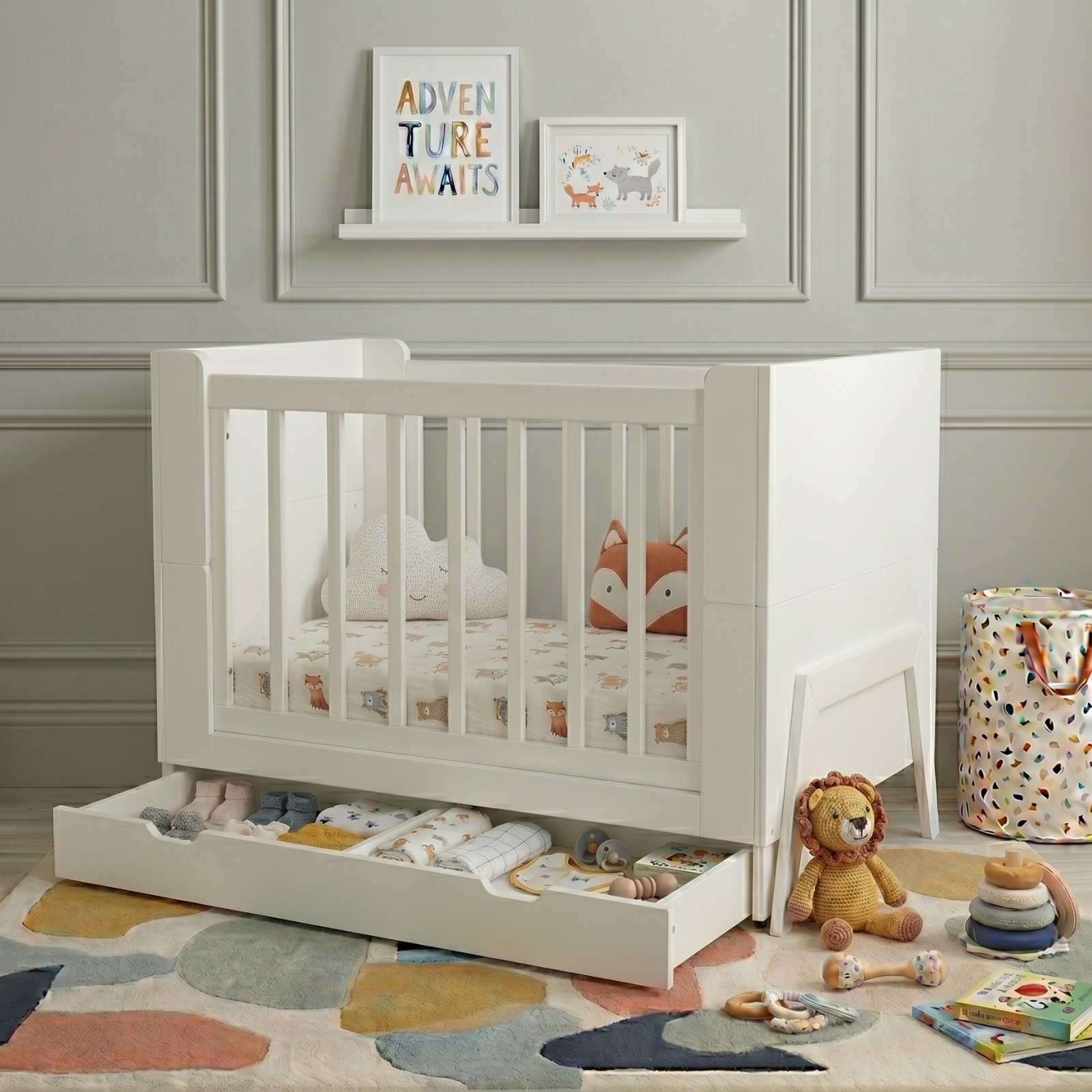 White crib in nursery corner with plush toys, storage drawer and geometric rug