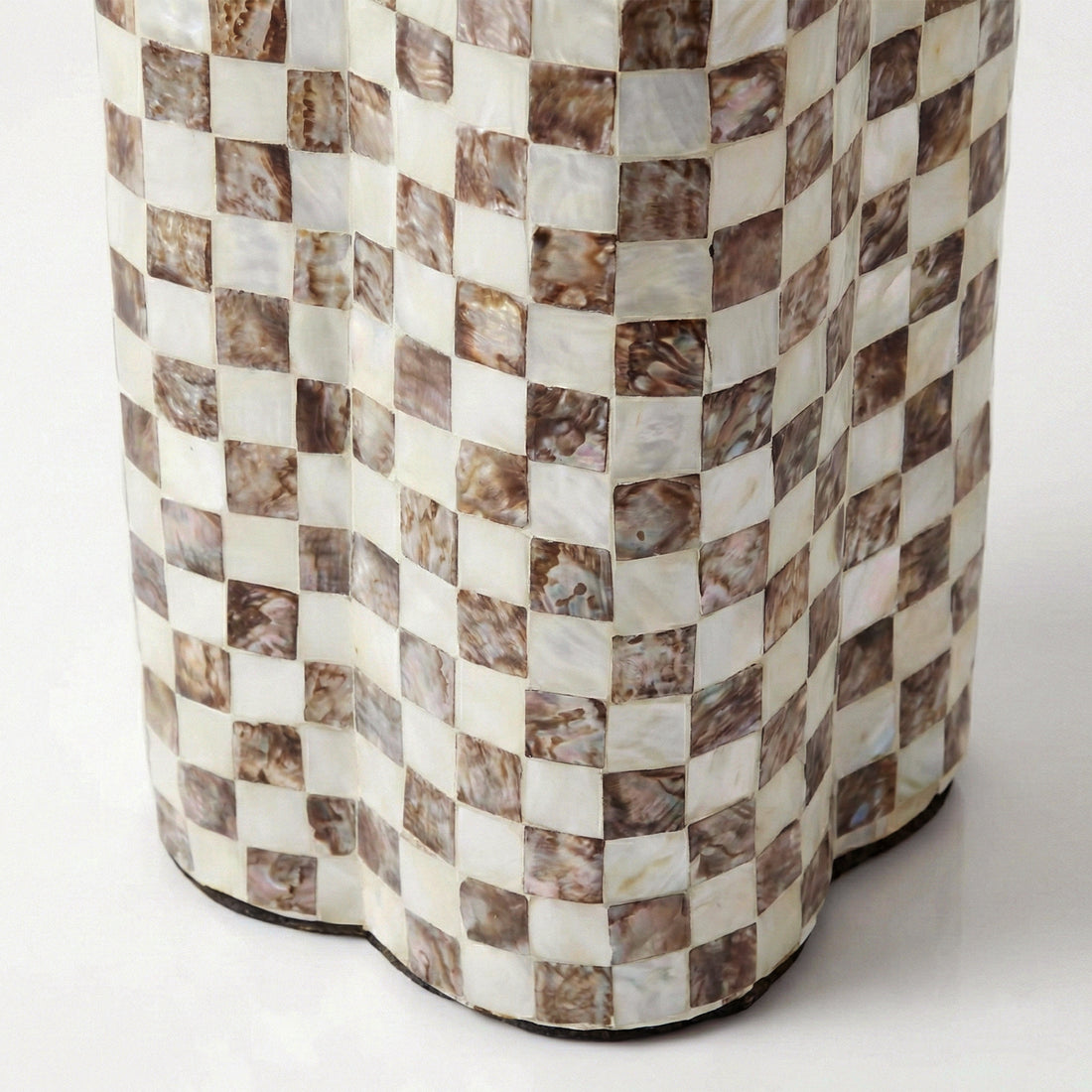 Detail of the lower section of a checkerboard-patterned table base on white background