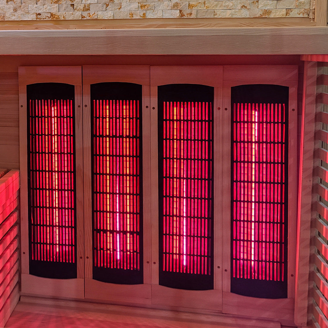 Infrared heating panels glowing red inside a wooden sauna interior.