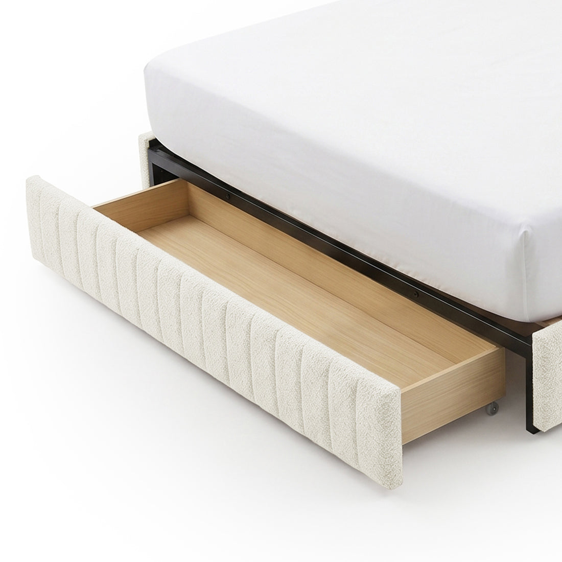 Close-up of upholstered bed corner with open under-bed drawer on white background