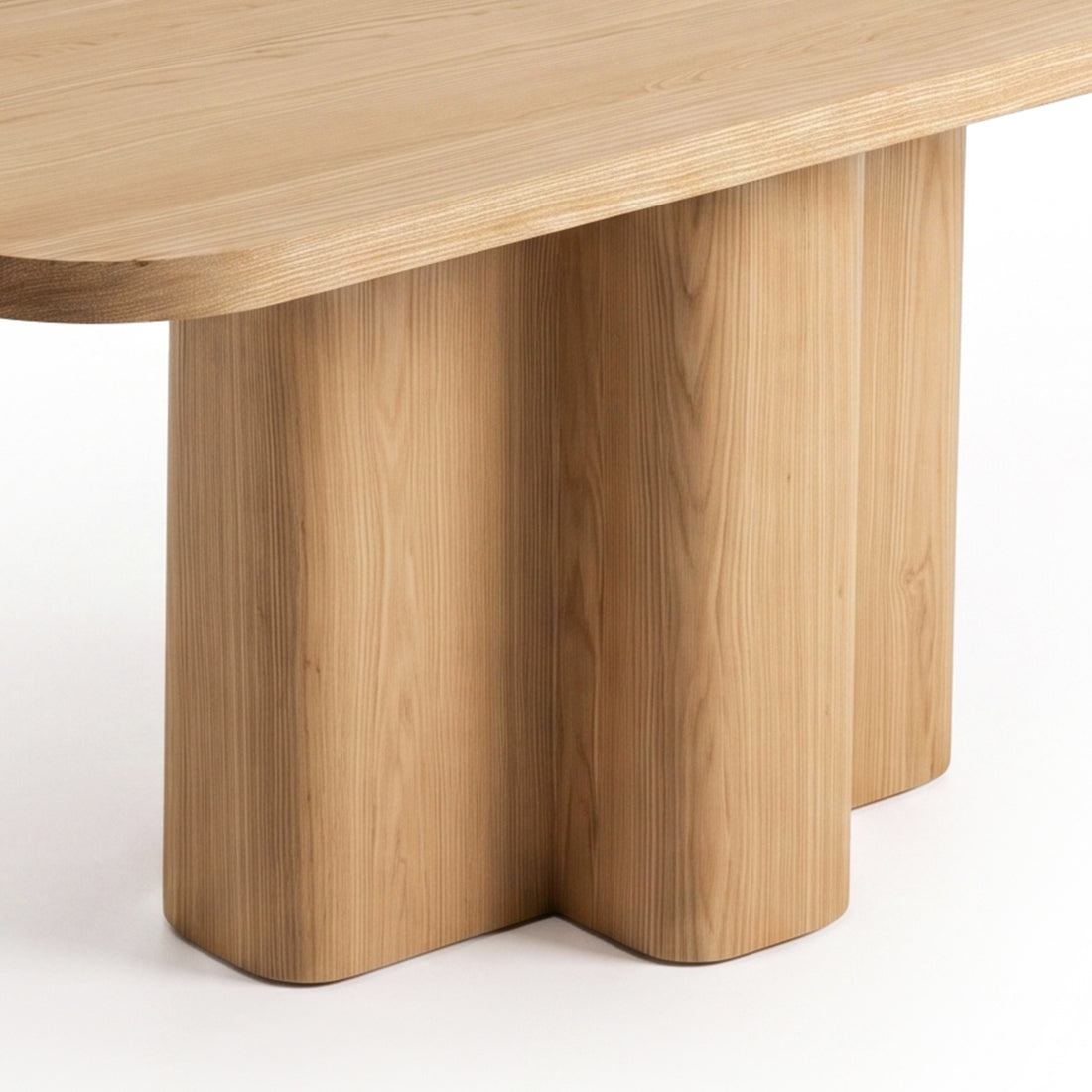 Close-up partial view of a wooden table corner and sculpted pedestal base on white background
